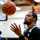 NBA球星训练投篮的侧面特写照片，篮球在空中飞行